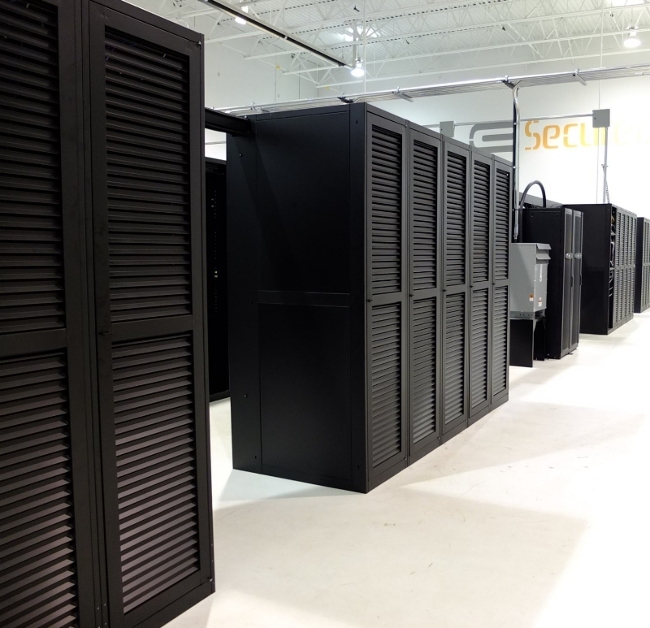An aisle of black louvred server cabinets running toward a wall carrying the eSecureData sign